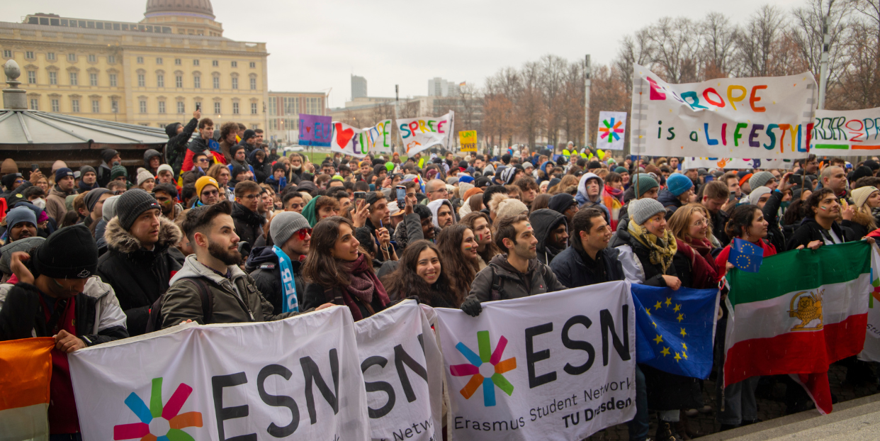 A big group of people standing together with posters and flags.