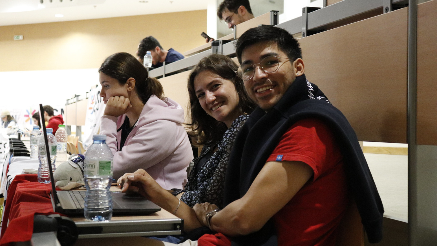 A photo of two students sitting in a classroom and smiling towards the camera.