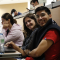 A photo of two students sitting in a classroom and smiling towards the camera.