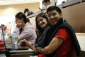 A photo of two students sitting in a classroom and smiling towards the camera.