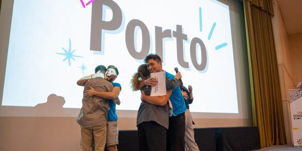 A picture of people hugging on a stage and a screen showing the word "Porto".
